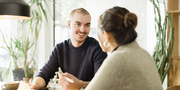Ein beratendes Gespräch zwischen zwei Personen in einem hellen Büro.