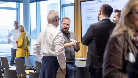 Mitarbeiter:innen in einer modernen Büroumgebung bei einer Diskussion in einem hellen Büro.